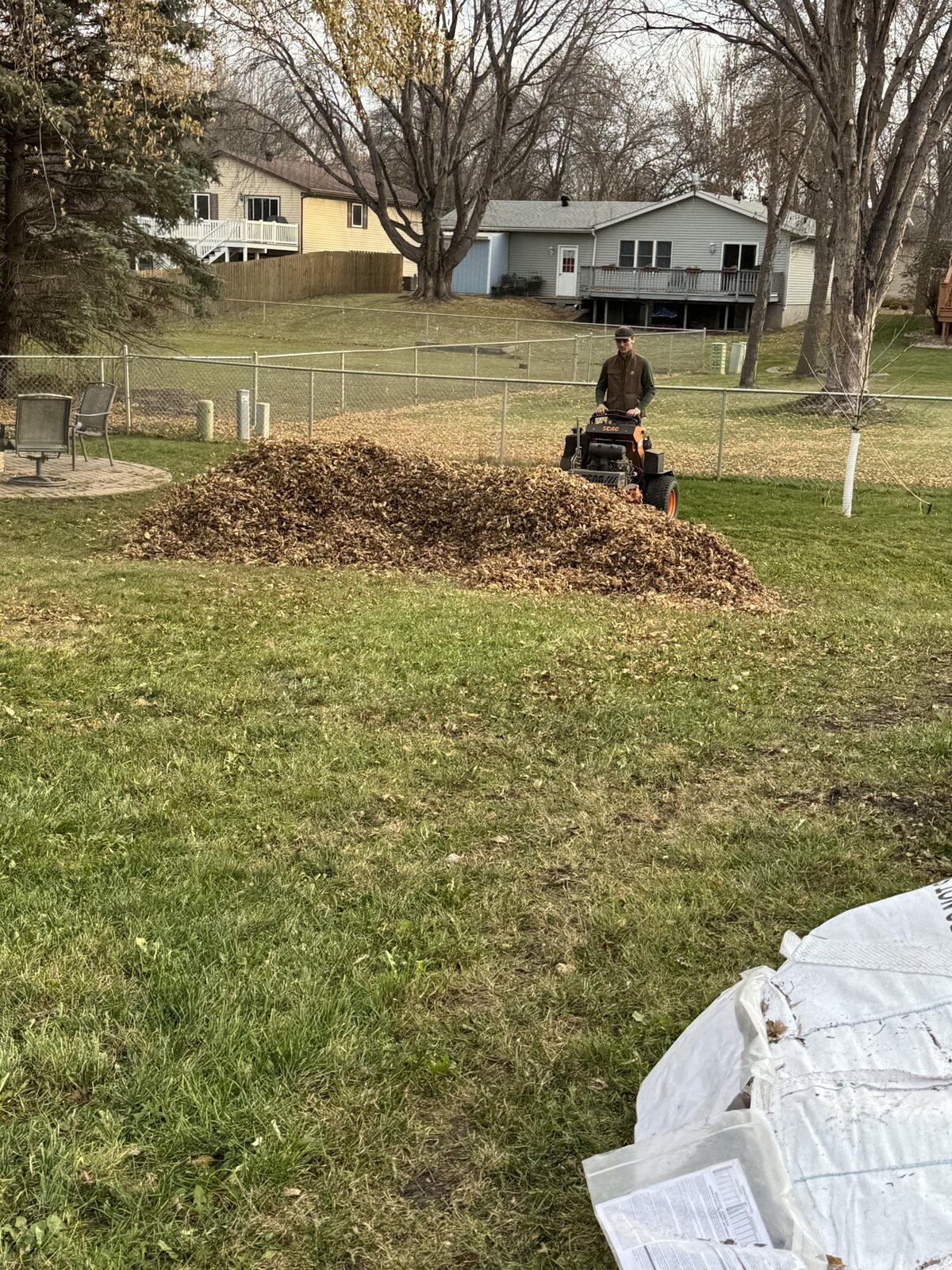 Perfect Turf fall cleanup with a mower collecting a large leaf pile in a backyard