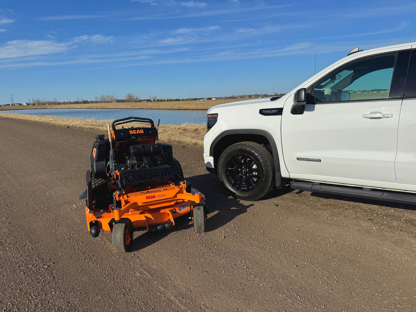 Perfect Turf Scag zero-turn mower next to white work truck under prairie sky