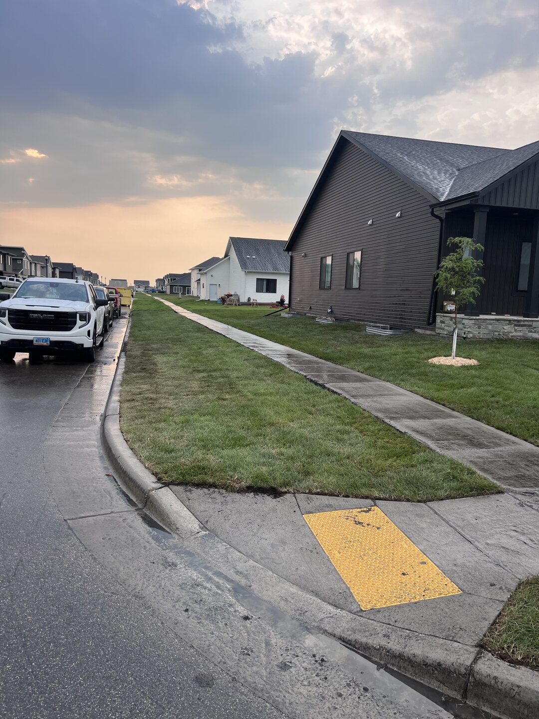 Second angle of a West Fargo sod installation along the sidewalk after rain